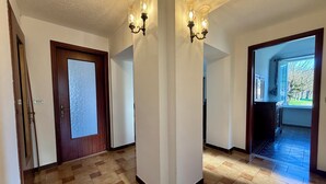 Un couloir doté d’un sol à carreaux, d’une porte en bois avec des vitres dépolies et de deux appliques murales avec des lampes.