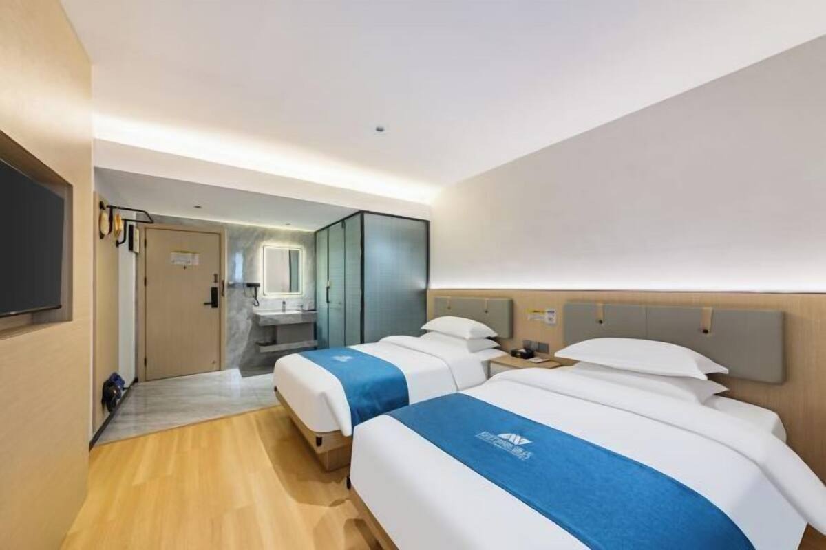 A hotel room with two beds, a bathroom, and a TV.