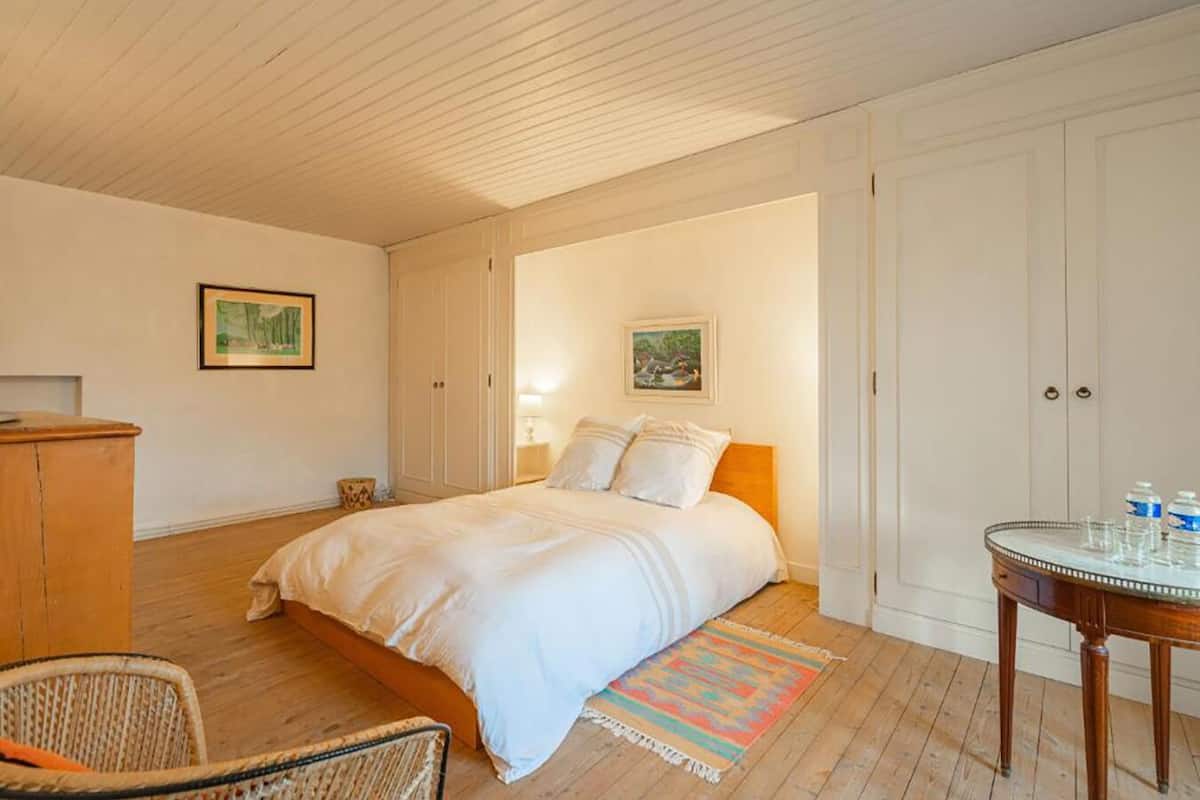 Ein Schlafzimmer mit einem Bett, einem Sessel, einem Schreibtisch und einem Kleiderschrank.