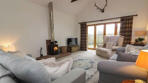 A cozy living room with a fireplace, comfortable seating, and a television. - The Stables (Thornhill)