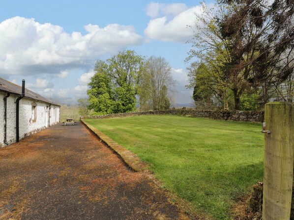 Een landweg die leidt naar een stenen muur en een wit gebouw met een schuin dak.