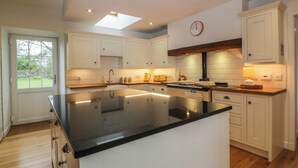 A modern kitchen with white cabinetry, a large island, and a skylight. - The Stables (Thornhill)