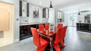 A modern kitchen with white cabinets, a black countertop, and a built-in oven. - 6 Bed House - Sleeps 11 - Pets - Garden - Parking (Northwood)