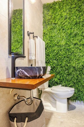 A bathroom with a marble sink, a toilet, and a green wall.