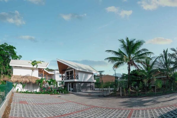A modern resort with a pool area, palm trees, and a two-story building with a balcony.