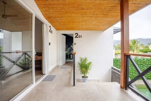 A modern hotel corridor with glass doors, a wooden ceiling, and a potted plant.