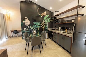 A modern kitchen with a dining area, featuring a large mural, a refrigerator, and a microwave.