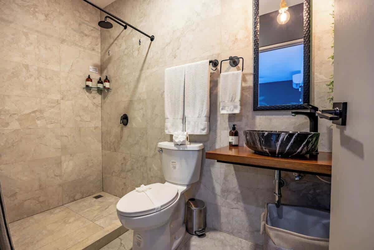 A modern bathroom with a shower, toilet, and sink.