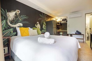 A hotel room with a large bed, a small kitchen area, and a bathroom.