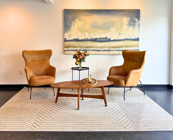 A room with two leather armchairs, a wooden coffee table, and a painting on the wall.