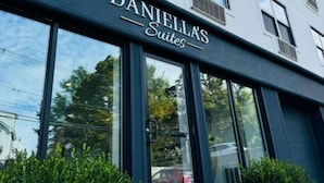 Un bâtiment moderne portant l’enseigne « DANIELLA’S Suites », ce qui indique qu’il s’agit d’un hôtel ou d’un établissement proposant des hébergements.