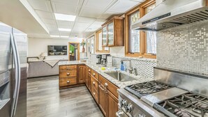Una cocina moderna con armarios de madera, una estufa de acero inoxidable y un salpicadero de azulejos.