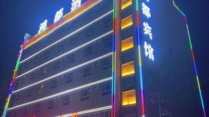 Un edifici d'hotel de diversos pisos amb senyalització il·luminada i bandes verticals de llum.
