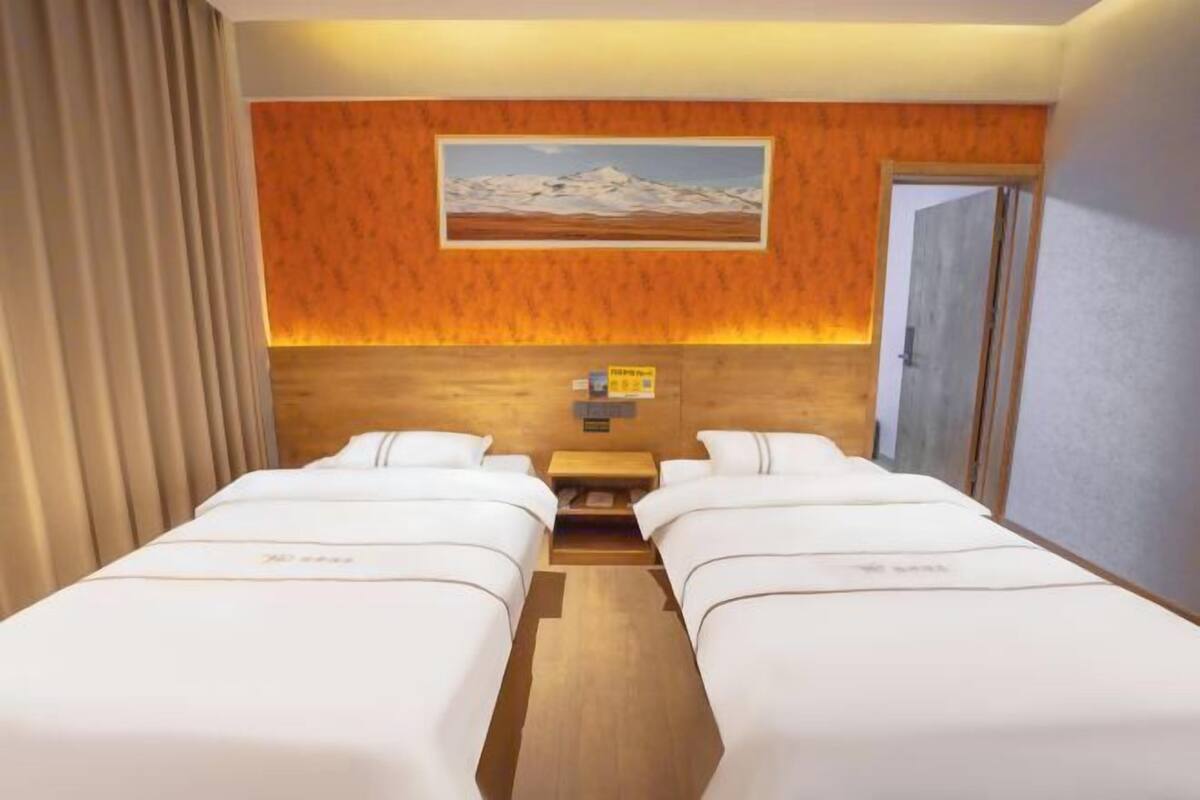 A hotel room with two beds, a wooden headboard, a painting of a mountain, and a wooden floor.