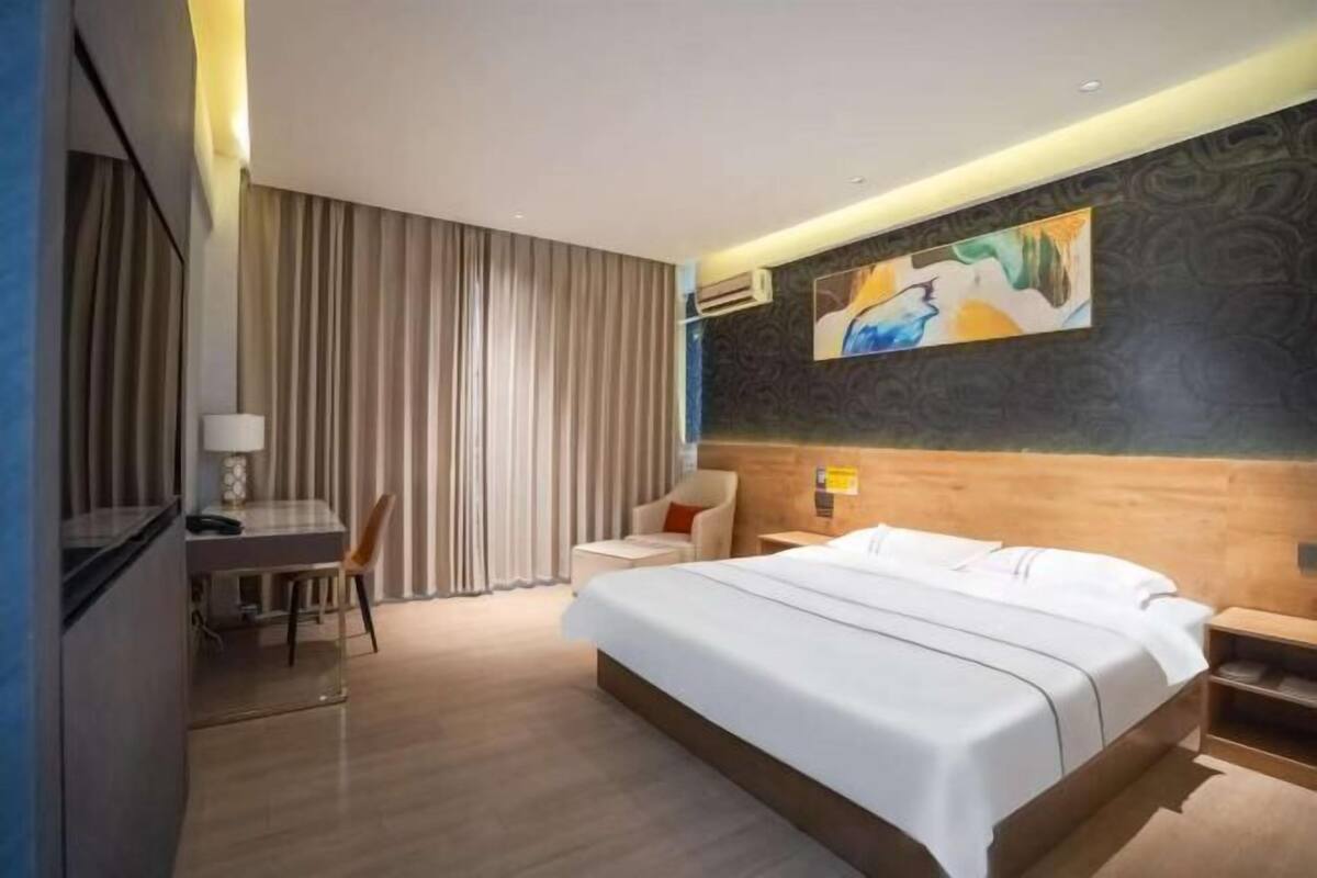A modern hotel room with a large bed, a desk, and a chair.