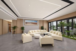 A modern lounge area with a curved sofa set, a coffee table, and potted plants. - Hongdu Hotel (Korla)