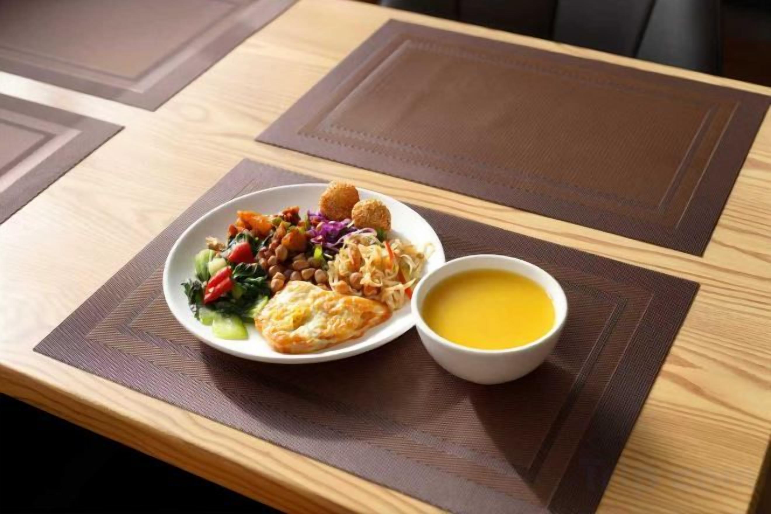 Een maaltijd met diverse gerechten en een kom soep op een tafel met placemats.