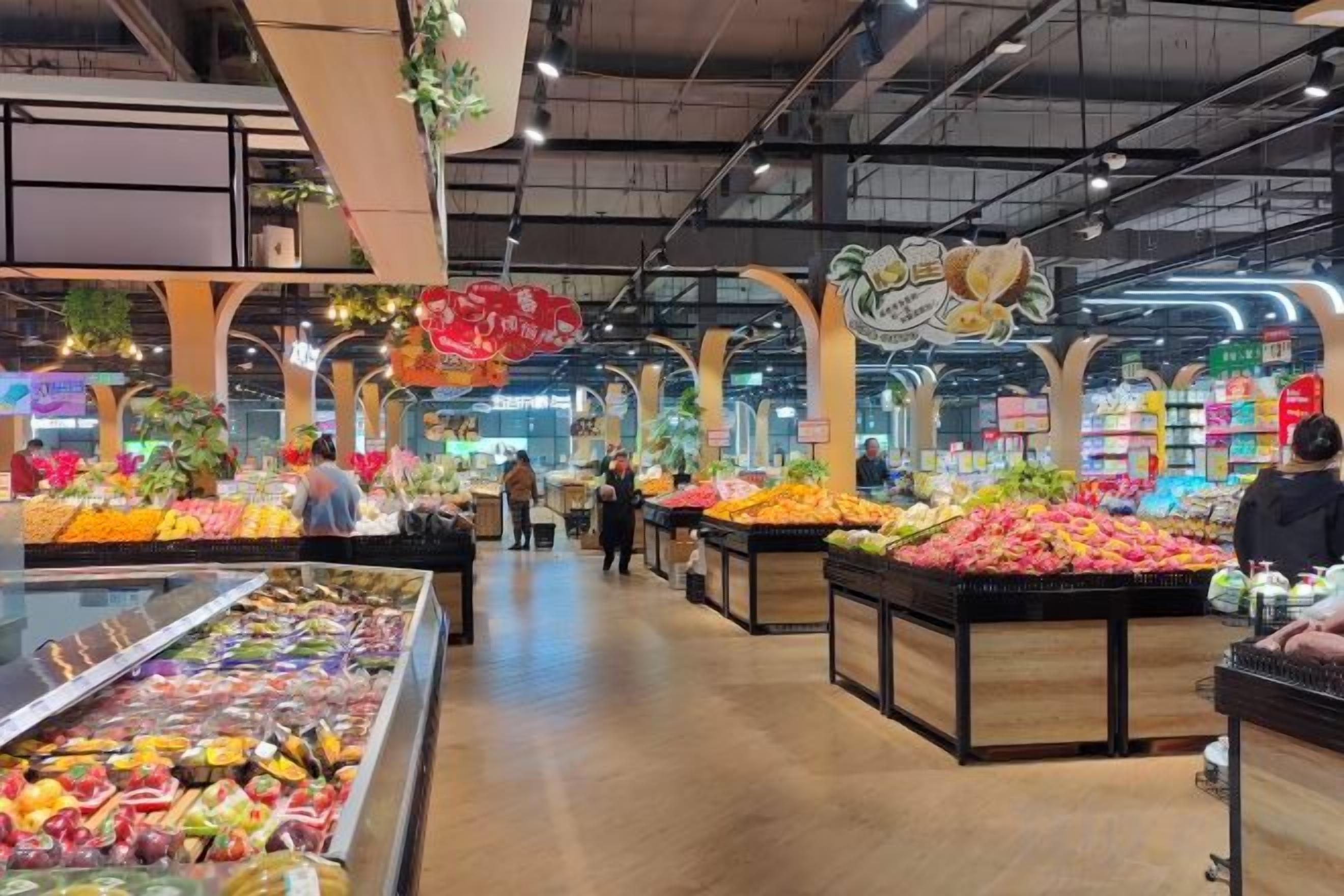 A grocery store interior with produce displays and refrigerated sections.