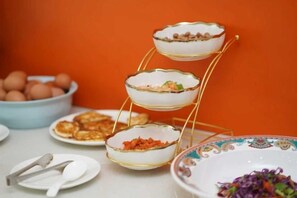 Un plat de service à étages contenant des aliments, un bol d’œufs et une assiette avec une salade.