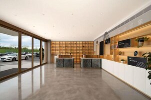 Una moderna área de recepción con un panel de vidrio, mostrador de madera y una exhibición de premios.