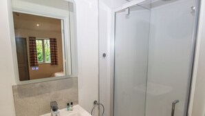 Un baño con lavamanos blanco, espejo y cabina de ducha de vidrio.