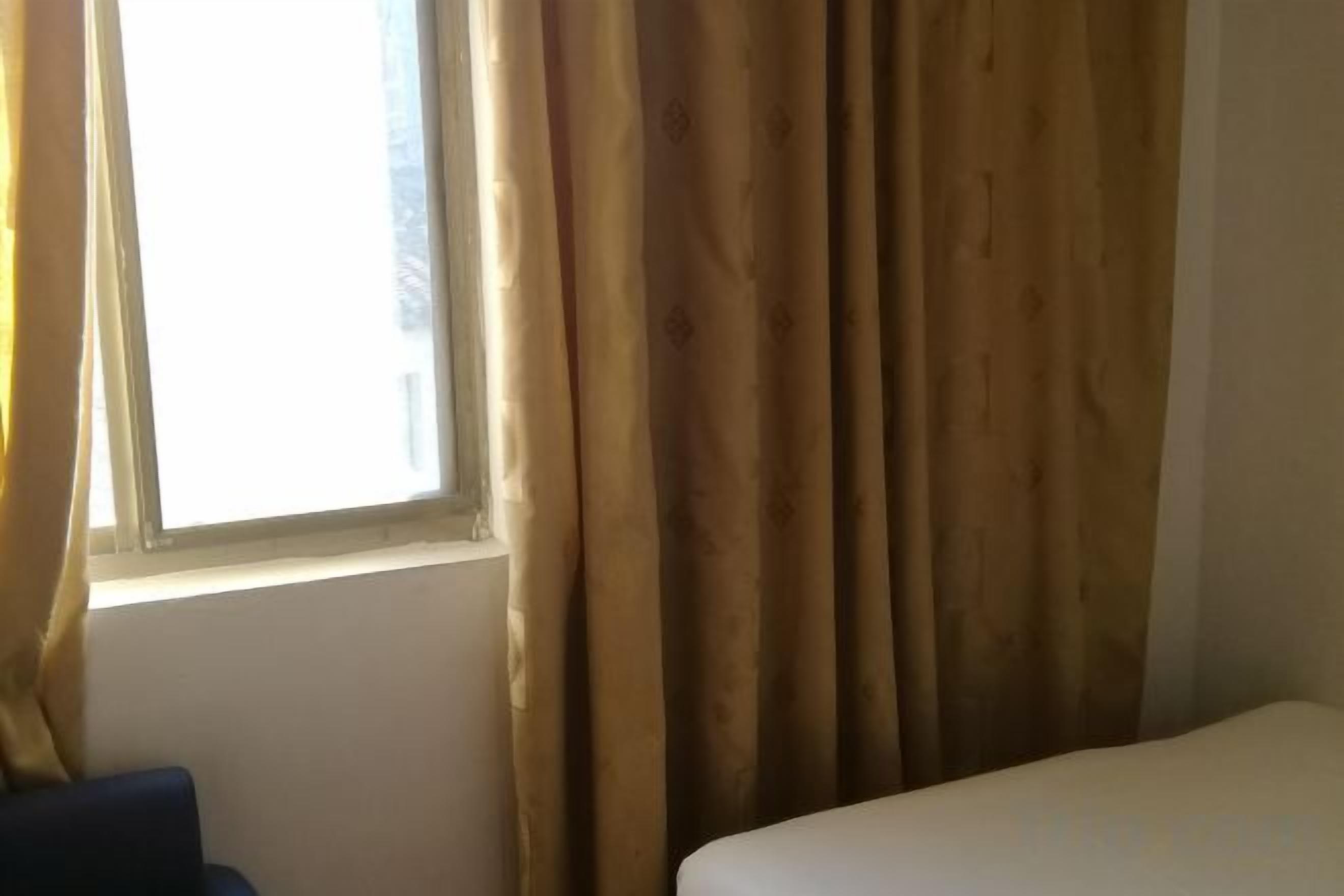 A room with a bed, a window with curtains, and a chair.