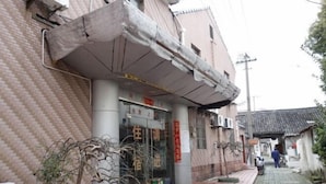 Un edificio con fachada de ladrillo, un local comercial con un letrero y una calle estrecha.