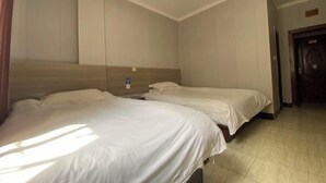 Habitación de hotel con dos camas, cabecero de madera, suelo de baldosas y una puerta.