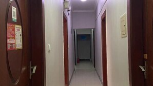 Un pasillo estrecho y bien iluminado, con puertas de madera y paredes blancas.