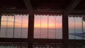 A view through a window with a scalloped design, overlooking a body of water and a distant shoreline.