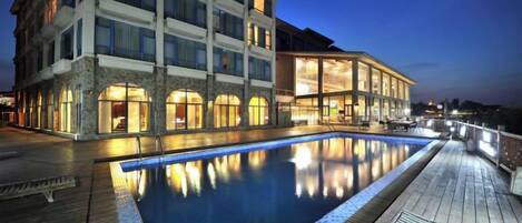 A hotel with a swimming pool, multiple balconies, and a waterfront view.