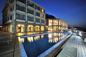 Un hotel con piscina, varios balcones y vista al agua.
