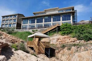 A modern hotel with a large building, a wooden structure with stairs, and a clear blue sky. - Beidaihe Bei Hua Yuan Sea View Hotel (Beidaihe Biluo Tower) (Qinhuangdao)