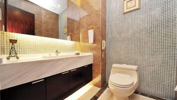 A modern bathroom with a marble sink, dark cabinets, a toilet, and a tiled wall.