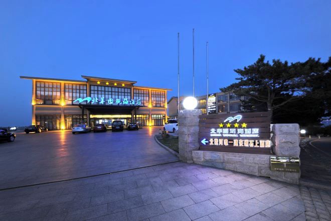 A hotel entrance with a sign indicating a 5-star rating, a parking lot, and a well-lit facade.