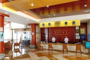 A reception area with a check-in counter, two receptionists, and a digital display board. - Beidaihe Bei Hua Yuan Sea View Hotel (Beidaihe Biluo Tower) (Qinhuangdao)