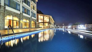 A swimming pool with a stone facade and large windows, reflecting the lights at night. - Beidaihe Bei Hua Yuan Sea View Hotel (Beidaihe Biluo Tower) (Qinhuangdao)