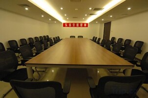 Un salón de conferencias con una larga mesa y varias sillas.
