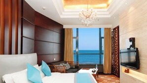 A hotel room with a large bed, a TV, a seating area, and a view of the ocean. - Beidaihe Bei Hua Yuan Sea View Hotel (Beidaihe Biluo Tower) (Qinhuangdao)
