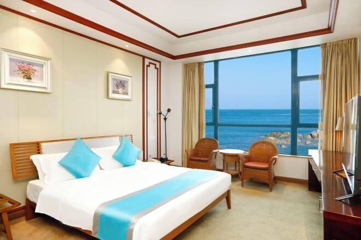 Una camera d'albergo con un letto, due poltrone, un tavolino e una televisione.