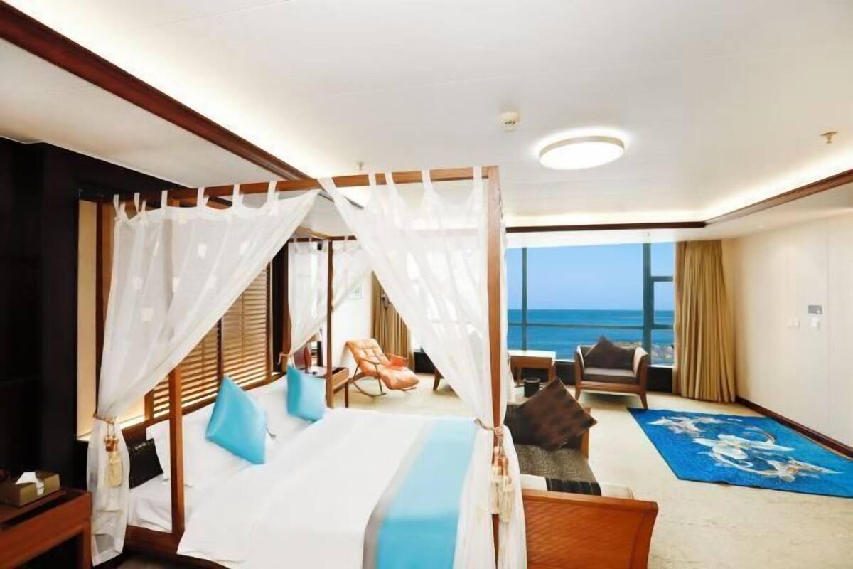 Una camera d'albergo con un letto, una sedia, vista sull'oceano e un balcone.