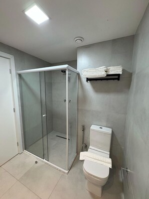 Moderni kylpyhuone, jossa on lasiseinällä varustettu suihku, wc ja pyyhekoukku.