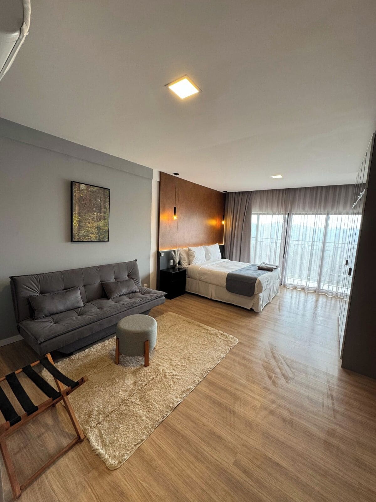 Uma sala de estar moderna com sofá, banquinho e cama com cabeceira.