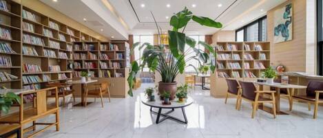 A library with bookshelves, tables, chairs, and potted plants.