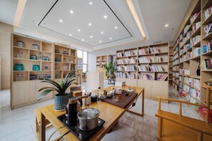 Une bibliothèque avec des étagères, une table en bois ornée d’une plante, et une autre étagère remplie de livres.