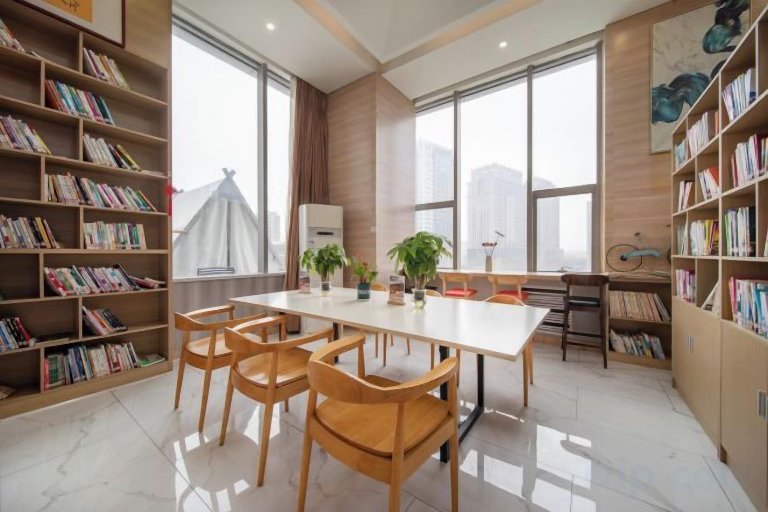 Um quarto espaçoso com uma grande mesa, várias cadeiras e estantes repletas de livros.