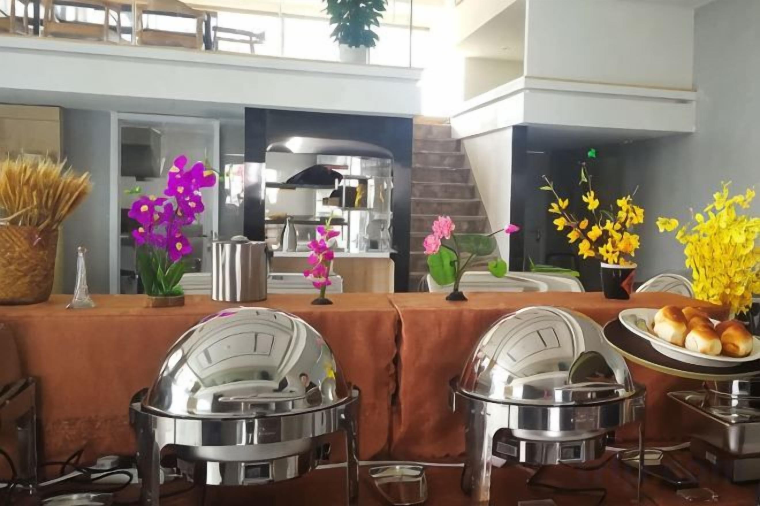 A buffet setup with multiple serving stations, a central food display, and decorative flowers.