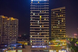 A high-rise hotel with multiple floors, illuminated windows, and a prominent sign at the top. - Timeless Hotel (Yantai)