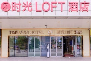 The entrance to the Timeless Hotel with a glass door and a visible fire hydrant outside. - Timeless Hotel (Yantai)