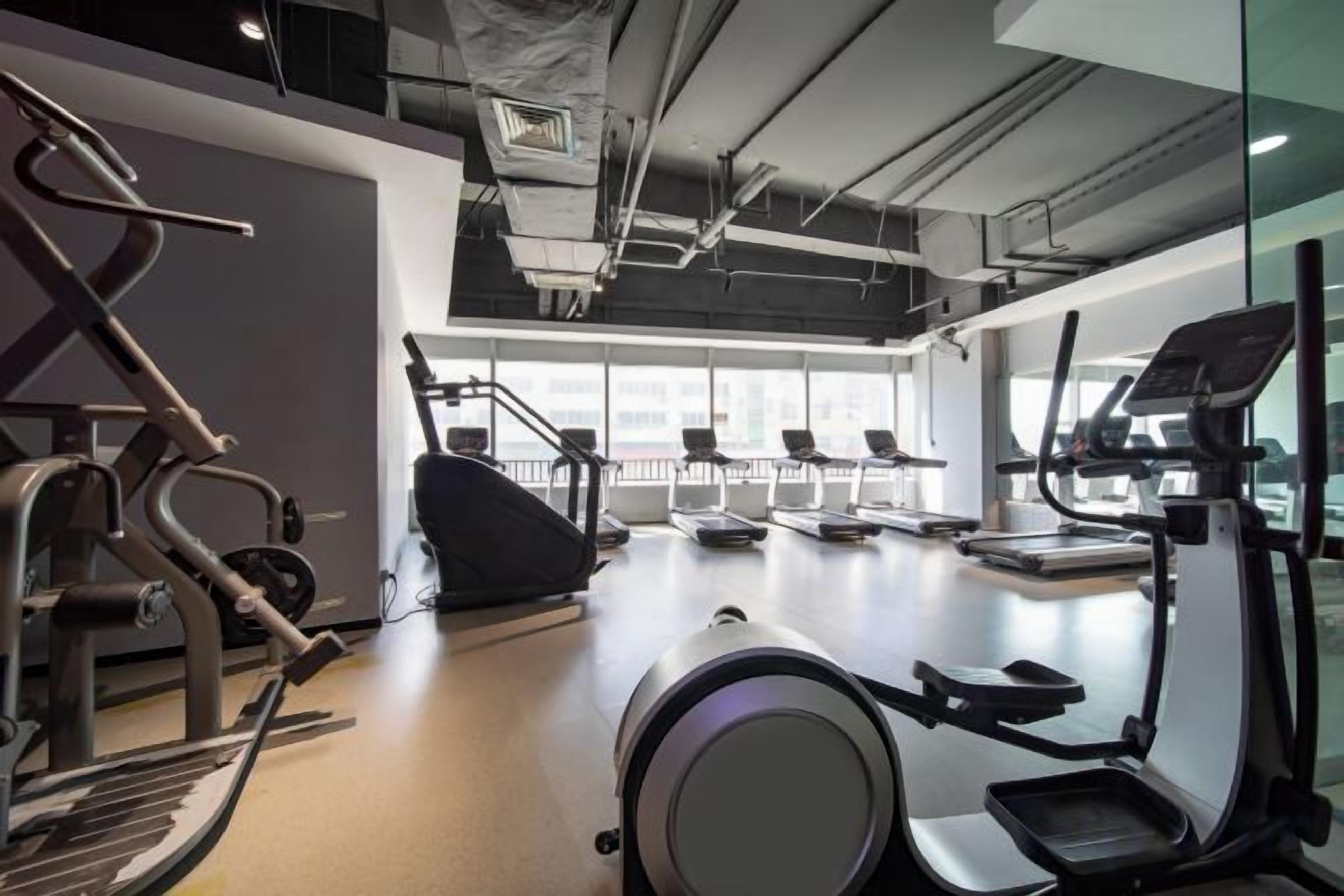 A gym with cardio equipment, a treadmill, and a rowing machine.